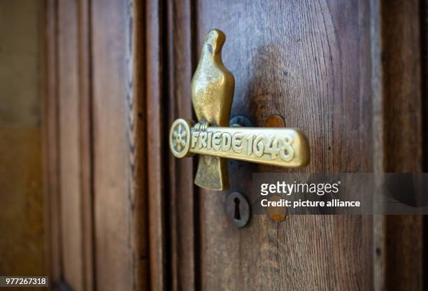 April 2018, Münster, Germany: The door knob of the door leading to the historic town hall, is dove shaped and made of bronze, with the words "Peace...
