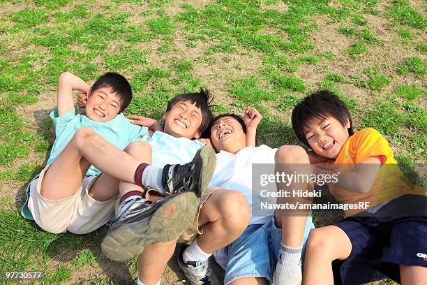 four boys lying on field laughing. futako-tamagawa, setagaya-ku, tokyo prefecture, japan - 子供のみ ストックフォトと画像