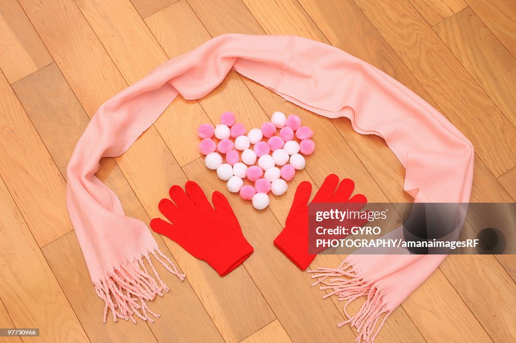 Gloves, scarf and pom poms on floor