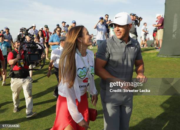 Brooks Koepka of the United States walks off the 18th green with girlfriend Jena Sims during the final round of the 2018 U.S. Open at Shinnecock...