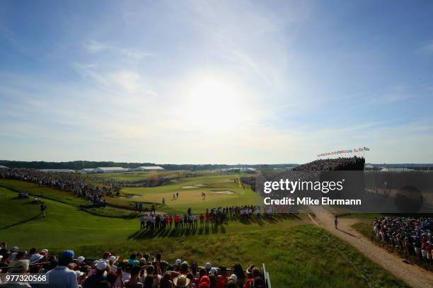 Brooks Koepka of the United States putts on the 18th green as a crowd looks on during the final round of the 2018 U.S. Open at Shinnecock Hills Golf...