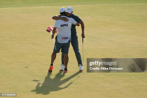 Brooks Koepka of the United States celebrates with caddie Richard Elliott on the 18th green during the final round of the 2018 U.S. Open at...