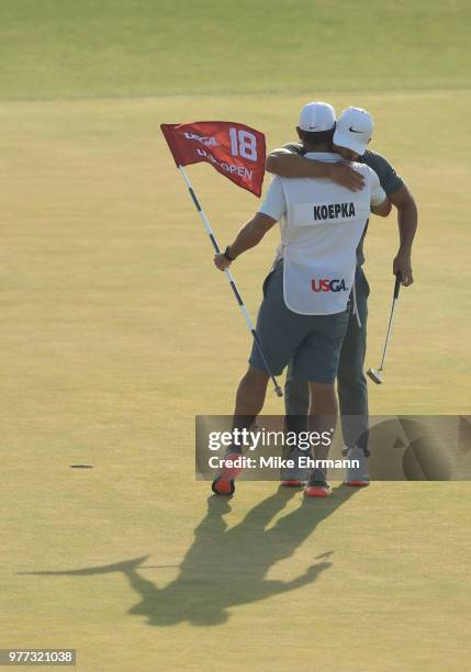 Brooks Koepka of the United States celebrates with caddie Richard Elliott on the 18th green during the final round of the 2018 U.S. Open at...