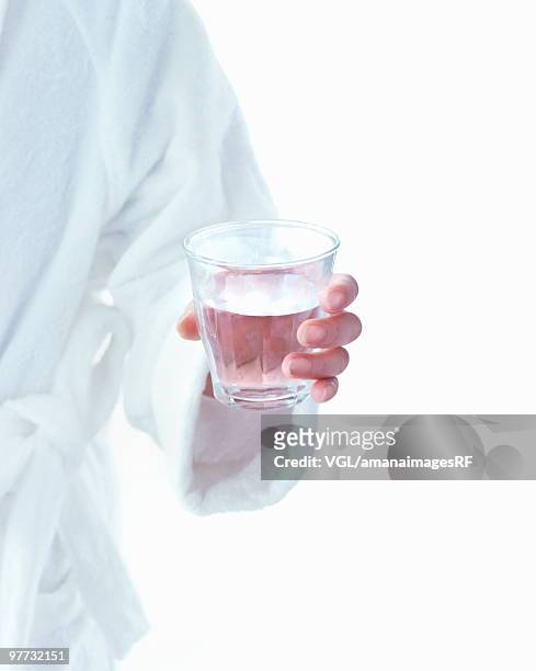 woman in bath robe holding glass of water - bath robe stockfoto's en -beelden