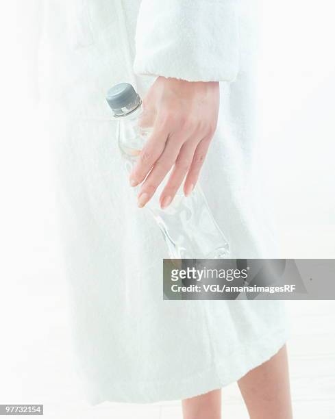 woman in bath robe holding bottled water - bath robe stockfoto's en -beelden