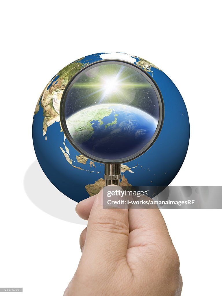 Man looking into globe though magnifying glass