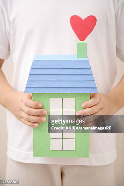 child holding a house with heart shape - creative rf stock-fotos und bilder