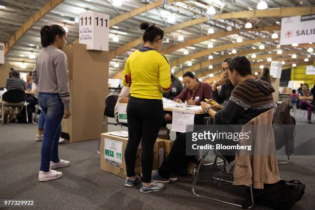 Polling officials verify a voter's identification inside the Corferias polling station during the second round of presidential elections in Bogota,...