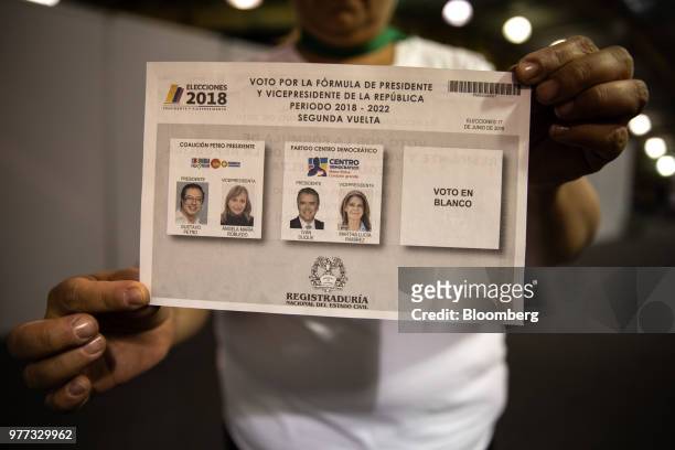 Polling official displays a blank ballot for a photograph inside the Corferias polling station during the second round of presidential elections in...