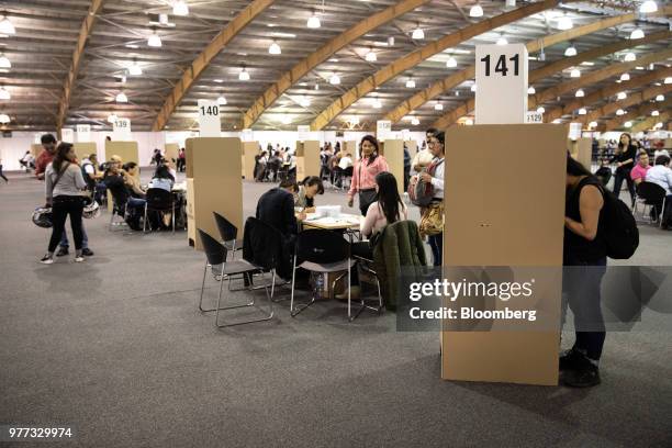 Voter marks a ballot at a booth as polling officials verify another's identification inside the Corferias polling station during the second round of...