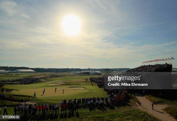 Fans watch Brooks Koepka of the United States and Dustin Johnson of the United States putts on the 18th green during the final round of the 2018 U.S....