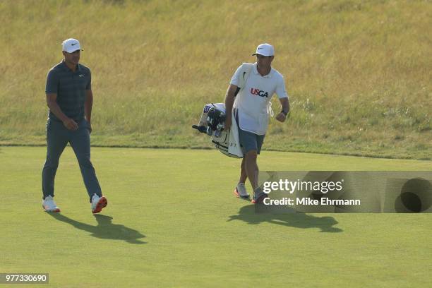 Brooks Koepka of the United States and caddie Richard Elliott walk off the 18th green during the final round of the 2018 U.S. Open at Shinnecock...