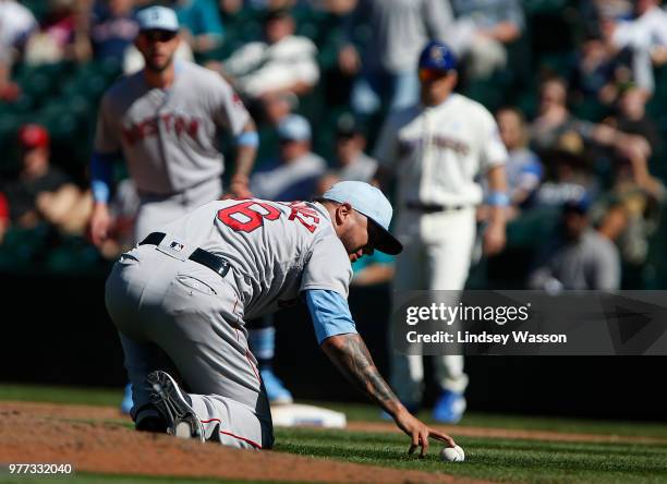 Hector Velazquez of the Boston Red Sox bends down to pick up the grounder by Andrew Romine of the Seattle Mariners to end the game at Safeco Field on...