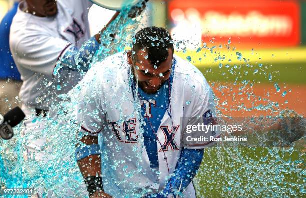 Jose Trevino of the Texas Rangers is doused by teammates after he hit a game winning two-run single against the Colorado Rockies in the bottom of the...