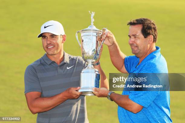 Brooks Koepka of the United States and his father Robert Koepka celebrate with the U.S. Open Championship trophy after winning the 2018 U.S. Open at...
