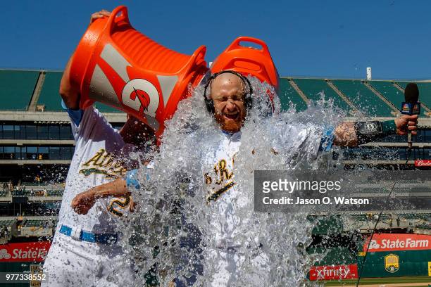 Stephen Piscotty of the Oakland Athletics and Chad Pinder pour water and Gatorade on Jonathan Lucroy after he hit a walk off single against the Los...