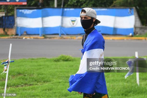 An anti-government demonstrator draped in the national flag takes part in a protest in Managua, Nicaragua on June 17 demanding justice for the death...