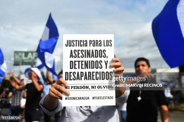 An anti-government demonstrator holds a sign while taking part in a protest in Managua, Nicaragua on June 17 demanding justice for the death of six...