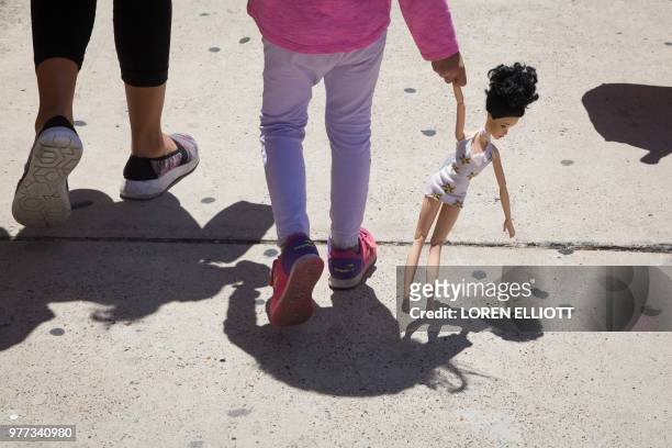 Year-old Honduran girl carries a doll while walking with her immigrant mother, both released from detention through the "catch and release" policy,...