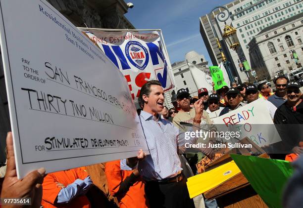 San Francisco Mayor Gavin Newsom holds a mock stimulus check as he speaks to union workers during a rally in support of a proposed stimulus reform...