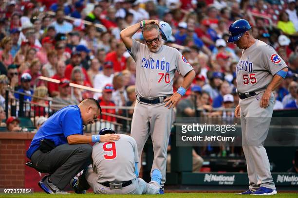 Joe Maddon and third base coach Brian Butterfield of the Chicago Cubs look on as Javier Baez is checked out by a trainer after he was hit by a pitch...