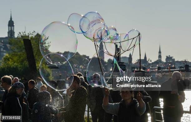 Dpatop - Soap bubbles glitter in the sun above people at the Fischmarkt, in Hamburg, Germany, 06 May 2018. Photo: Axel Heimken/dpa