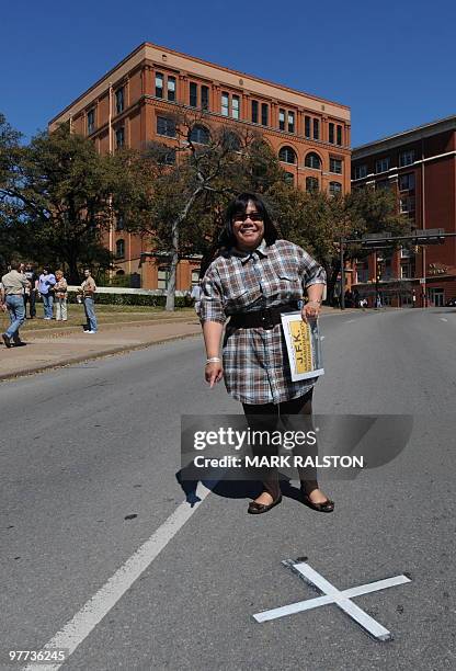 Tourist poses for photos on March 13, 2010 at the spot in front of the former Texas School Book Depository Building in Dealey Plaza, where the 1963...