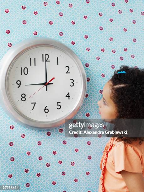 girl looking at clock - wandklok stockfoto's en -beelden