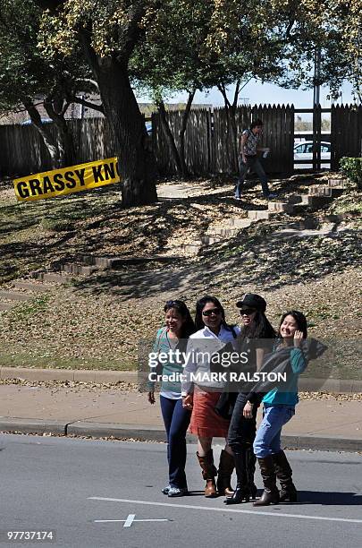 Tourists view the cross on Elm St indicting the location of the presidential motorcade when the first shot that was fired, in front of the Grassy...