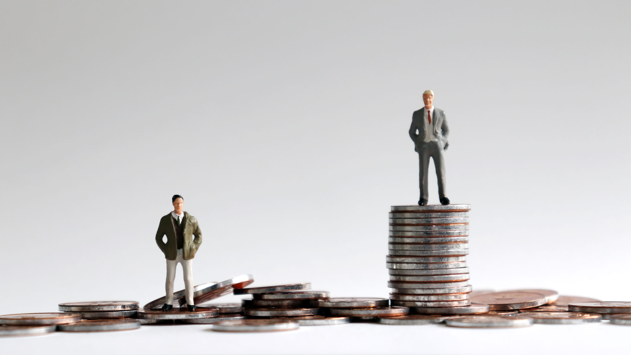 Miniature people standing on a pile of coins. Miniature people standing on a pile of coins.