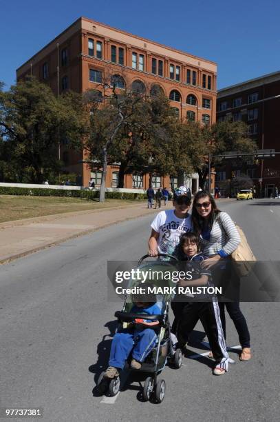 Tourists pose for family photos on March 13, 2010 at the spot in front of the former Texas School Book Depository Building in Dealey Plaza, where the...