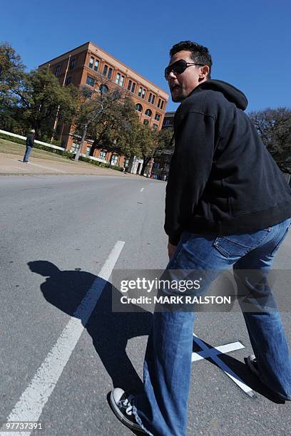 Tourist poses for a family photo on March 13, 2010 at the spot in front of the former Texas School Book Depository Building in Dealey Plaza, where...