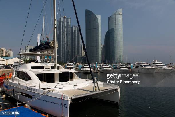 Yachts and boats sit moored at the marina as commercial and residential buildings stand in the background at the Haeundae district in Busan, South...
