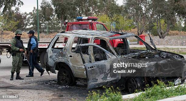 Members of the Mexican Federal Police guard on March 15, 2010 a burnt SUV found on the outskirts of Ciudad Juarez, which is apparently linked to the...