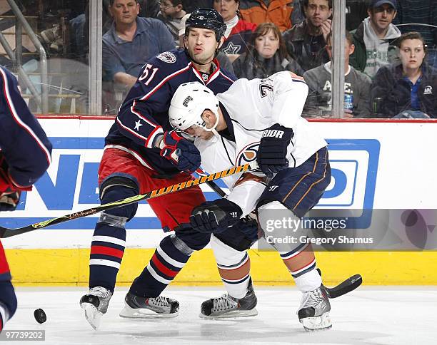 Fedor Tyutin of the Columbus Blue Jackets tries to keep the puck from Marc Pouliot of the Edmonton Oilers on March 15, 2010 at Nationwide Arena in...