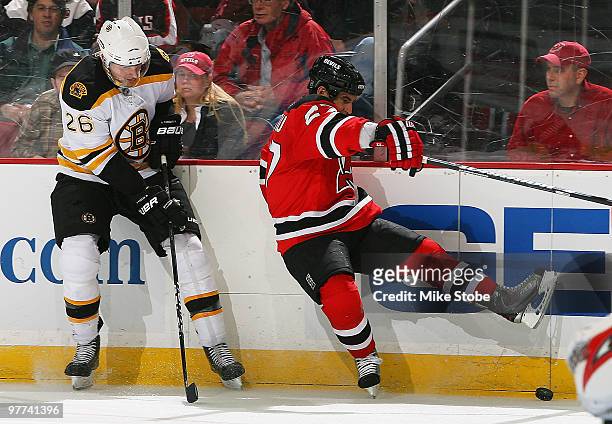 Mike Mottau of the New Jersey Devils looses his footing playing the puck as Blake Wheeler of the Boston Bruins pursues at the Prudential Center on...