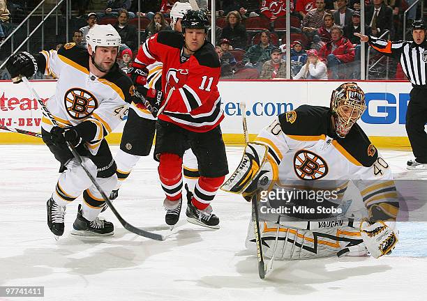 Goaltender Tuukka Rask of the Boston Bruins maers a save as teammate Mark Stuart and Dean McAmmond of the New Jersey Devils look for the rebound at...