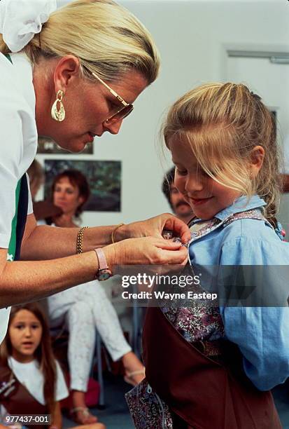 girl (5-7) receiving badge from woman leader in hall - girl guides badges stockfoto's en -beelden