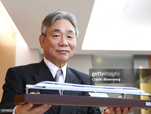 Yoshiyuki Kasai, chairman of Central Japan Railway Co., poses for a photograph with a model of magnetic-levitation train after an interview in Tokyo,...