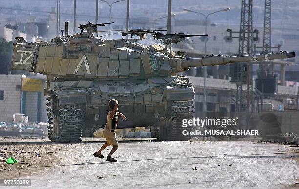 Palestinian child throws a stone at an Israeli tank on a road at the Palestinian Daheisheh refugee camp on the outskirts of West Bank town of...