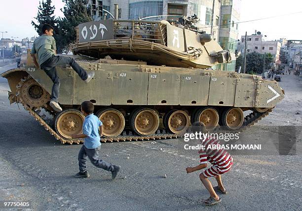 Palestinian boy climbs atop an Israeli tank after clashes erupted in the al-Amari refugee camp in the West Bank city of Ramallah 17 September 2002...