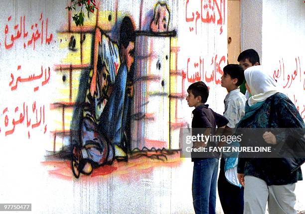 Palestinians look at a mural in Gaza City 22 October 2000, dedicated to the tragic death of 12-year-old fellow Palestinian Mohamed al-Durra who was...