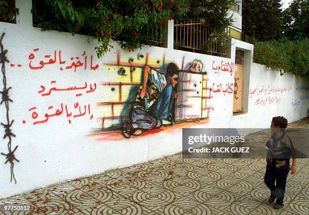 Palestinian boy passes in front of a mural in Gaza City 15 October 2000, dedicated to the tragic death of 12-year-old fellow Palestinian Mohamed...