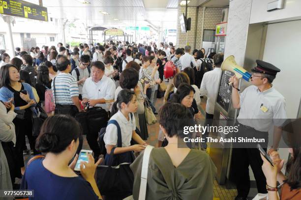 Passengers wait for service restart after the magnitude 6.1 strong earthquake suspend the Hankyu Railways service at Shukugawa Station on June 18,...