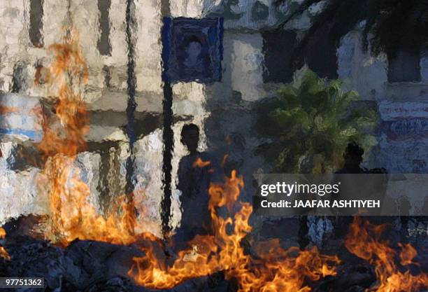 Palestinian boy looks at clashes with the Israeli army through the haze of burning tires, 23 August 2003, during clashes in the West Bank city of...