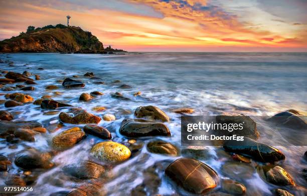 seascape lighthouse with rock beach at lanta island in sunset, krabi province, thailand - steinschlag stock-fotos und bilder