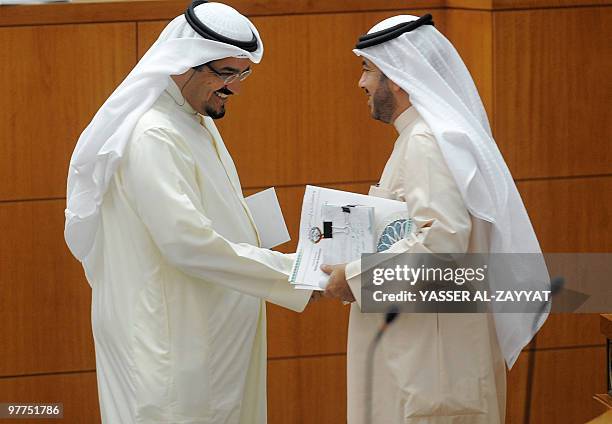 Kuwait's Information Minister Sheikh Ahmad Abdullah al-Sabah shakes hands with opposition MP Ali al-Deqbasi during a parliamentary session at the...