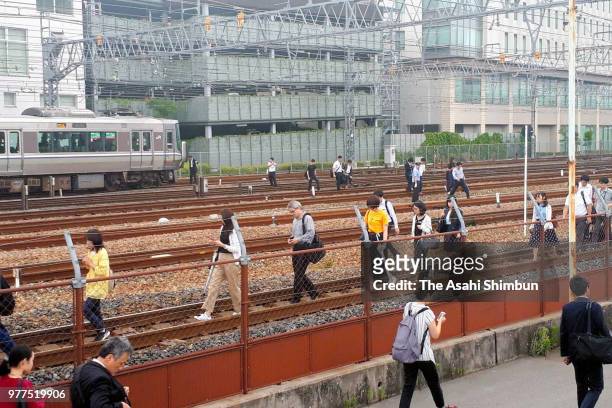 Passengers of a Hankyu Railways walk on the rail track after the magnitude 6.1 strong earthquake suspend the train service on June 18, 2018 in...