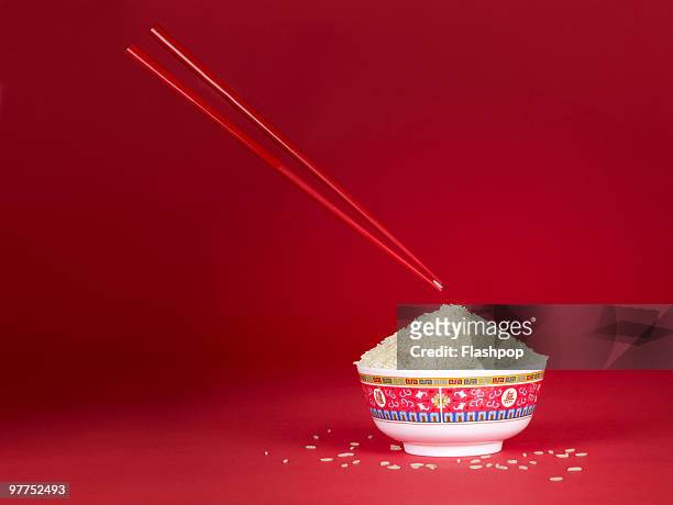 a pair of chop sticks holding a grain of rice - chopsticks stock pictures, royalty-free photos & images