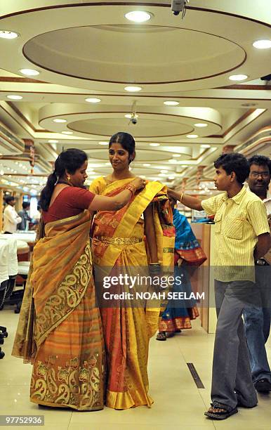 Indian woman has a saree fitted by a saleswoman during the launch of a wedding collection at a mall in Hyderabad on March 16, 2010. An Indian wedding...